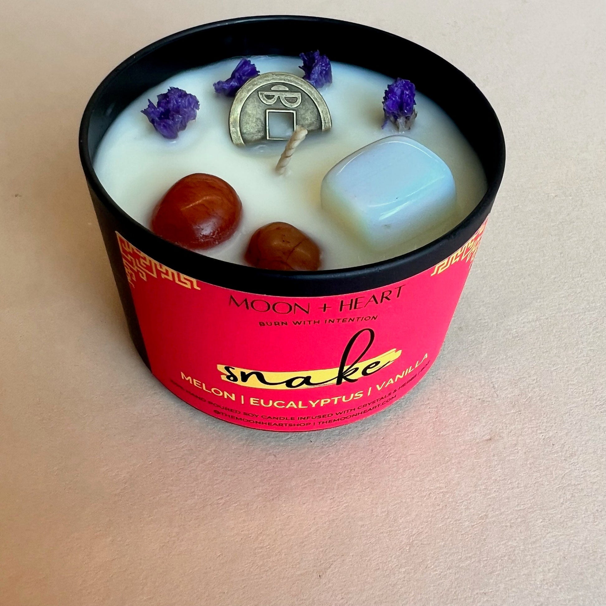 chinese zodiac snake candle infused with feng shui coin, carnelian and moonstone. Scented melon eucalyptus and vanilla.